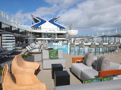 The spacious pool deck of the Celebrity Ascent, with sunbathers and a scenic ocean backdrop.
